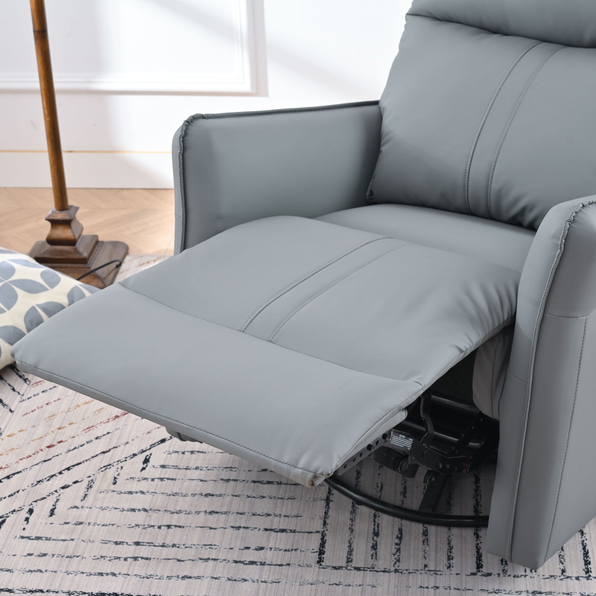 A 360° Modern Small Rocking Swivel Recliner Chair With Side Pocket, shown with its footrest extended, rests on a patterned rug beside a floor lamp and geometric pillow in a cozy, well-lit living room.