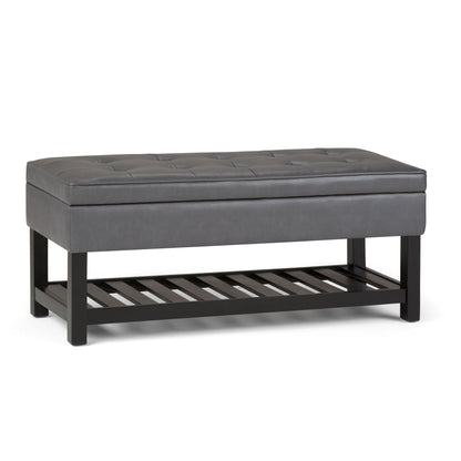 The Cosmopolitan - Storage Ottoman Bench With Open Bottom features a rectangular gray tufted padded seat, black wooden legs, and a slatted storage shelf, shown against a white background.