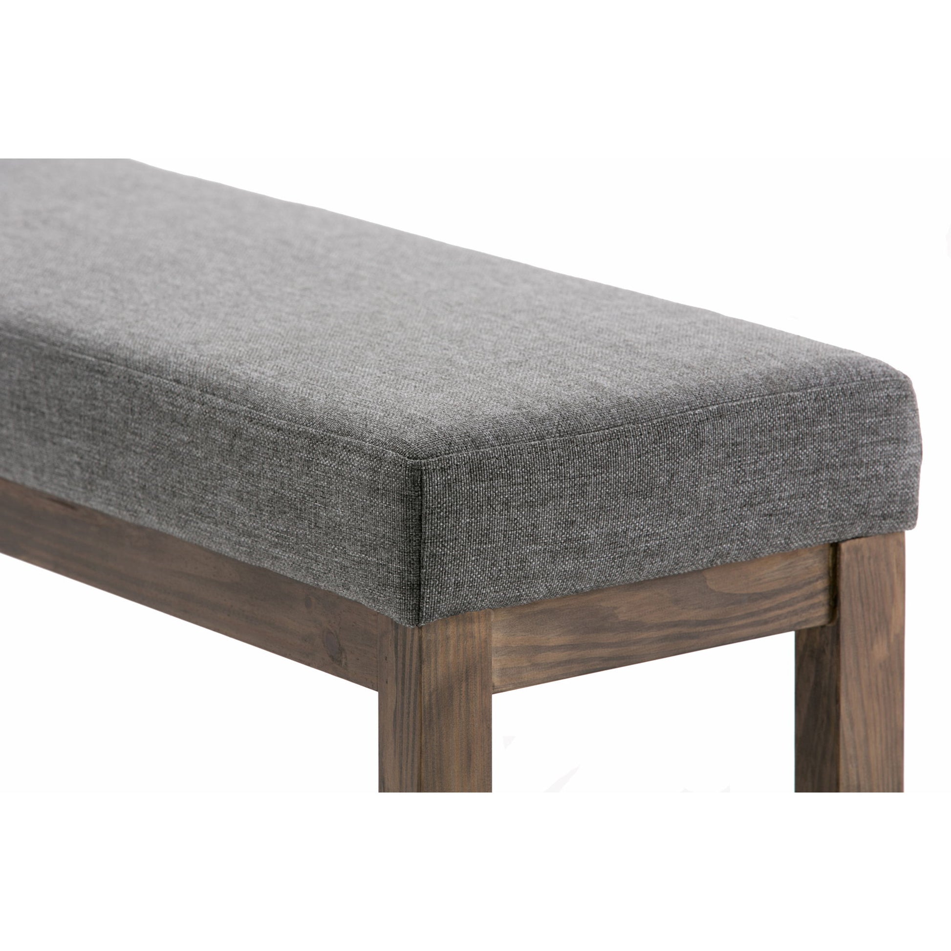 A close-up of the Milltown Upholstered Ottoman Bench, featuring a gray upholstered cushion and wooden legs, shown at an angle to showcase the fabric's texture and the natural wood grain.