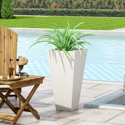 An Outdoor Modern Cast Stone Planter with long, green leaves sits on a poolside patio next to a wooden chair and table, with the pool and green lawn in the background.