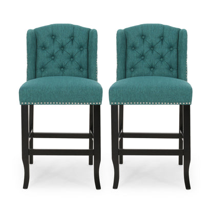 The Vienna Fabric Tufted Counter Stool With Nailhead Accents (Set of 2) features teal upholstery, tufted backs, silver nailhead trim, and dark wooden legs, shown side by side against a white background.