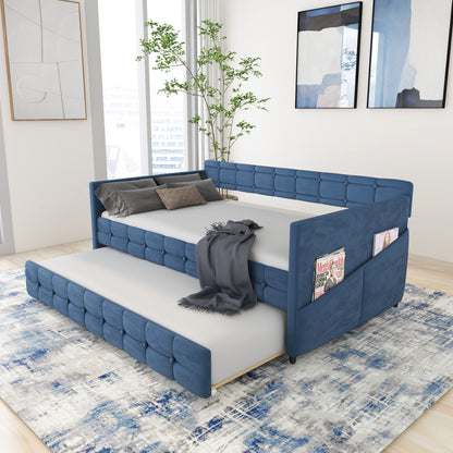 A modern bedroom features the Upholstered Twin Size Daybed Bed Frame with Trundle in blue velvet and studding design. The daybed has a gray blanket, pillows, side pockets for magazines, with abstract art above and a blue-patterned rug below.