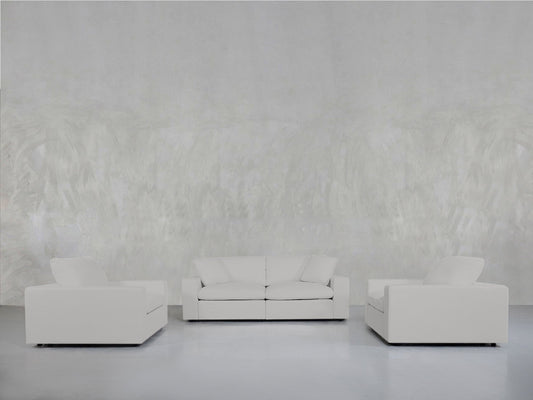 A minimalist living room features the 2-1-1 Sofa & Armchair Set in white, centered and flanked by matching armchairs against a light gray textured wall and smooth, pale flooring.