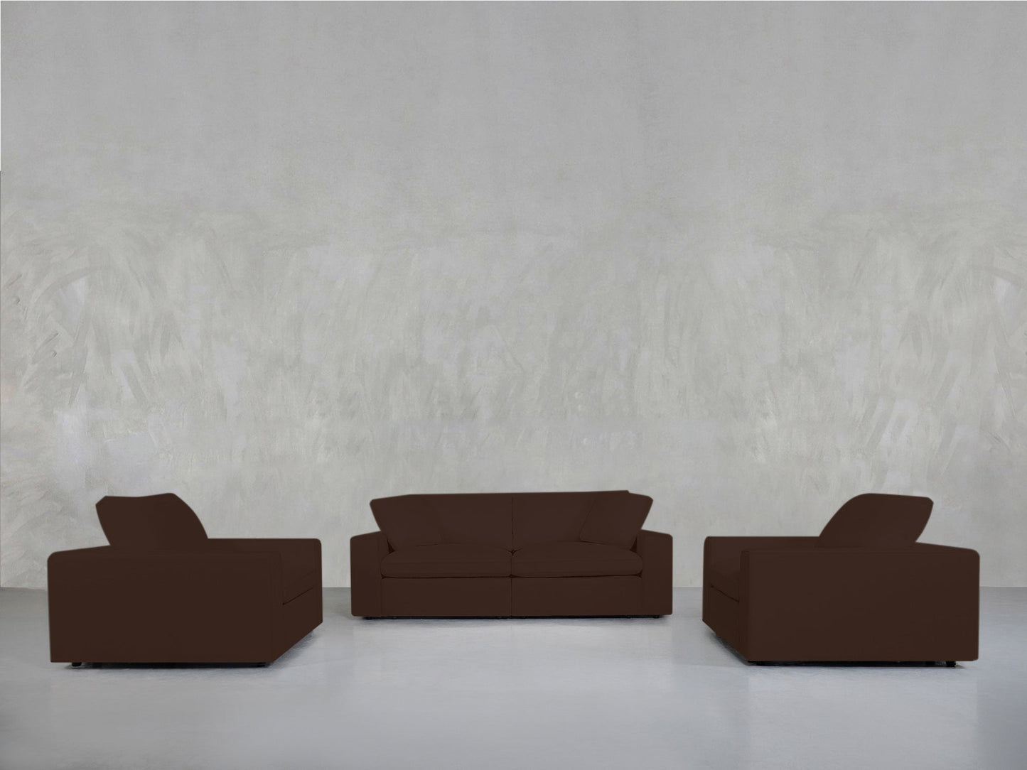 The 2-1-1 Sofa & Armchair Set, featuring a three-seater sofa and two armchairs in dark brown with simple, boxy designs, is arranged in a minimalist room with a light gray wall and floor.