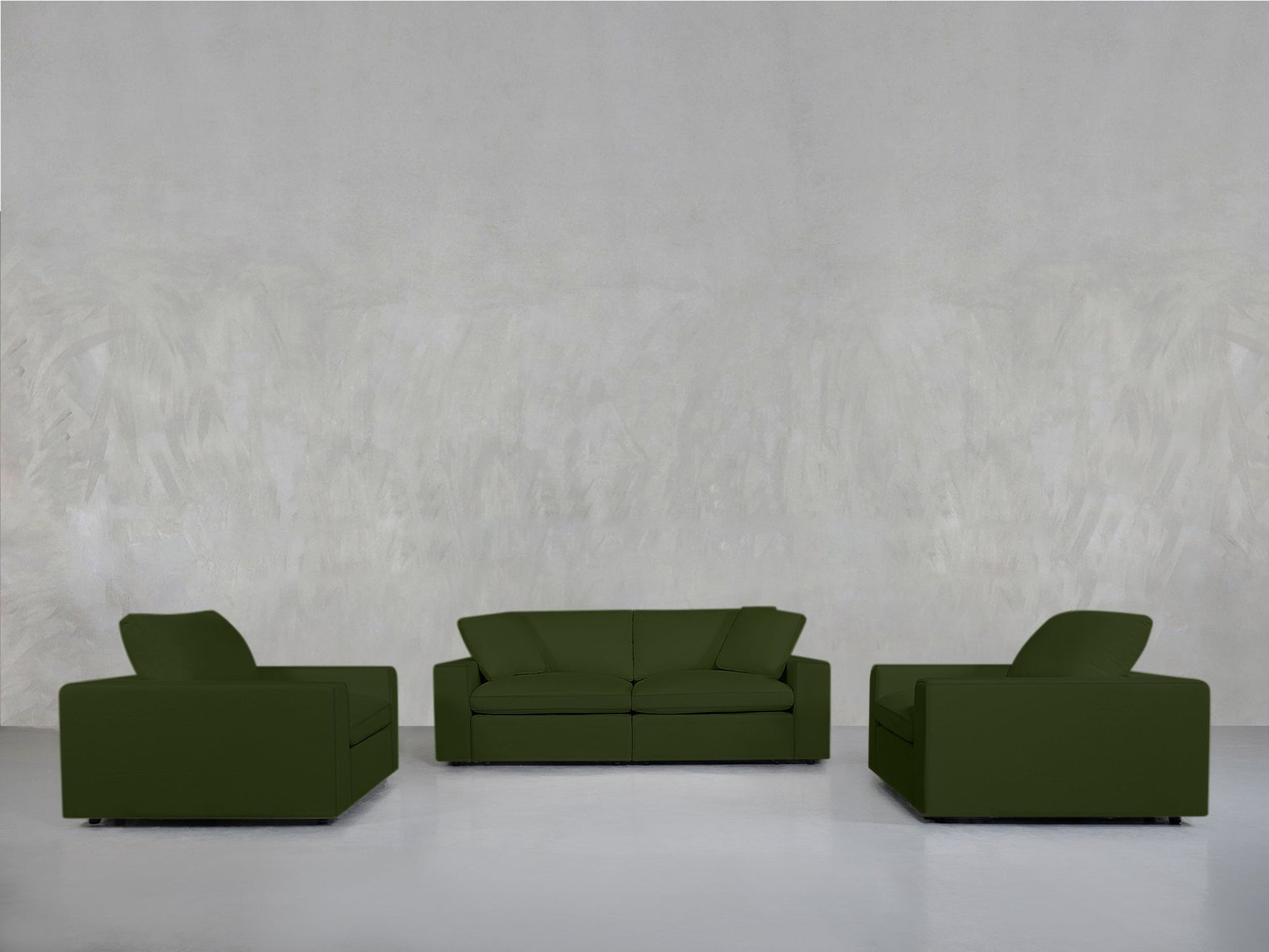 A minimalist room with a light gray textured wall showcases the 2-1-1 Sofa & Armchair Set, featuring a green loveseat at the center flanked by matching armchairs, all placed on a shiny white floor.