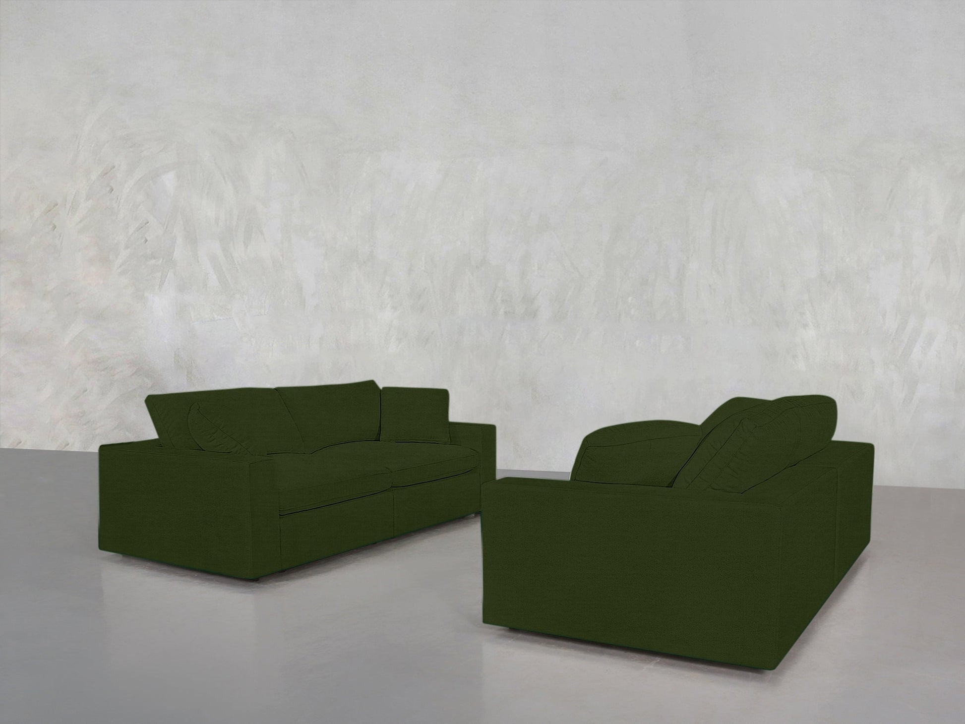 The 2-2 Sofa Set, in dark green, is arranged facing each other in a minimalist room with light gray walls and a smooth gray floor, creating a simple and uncluttered setting.