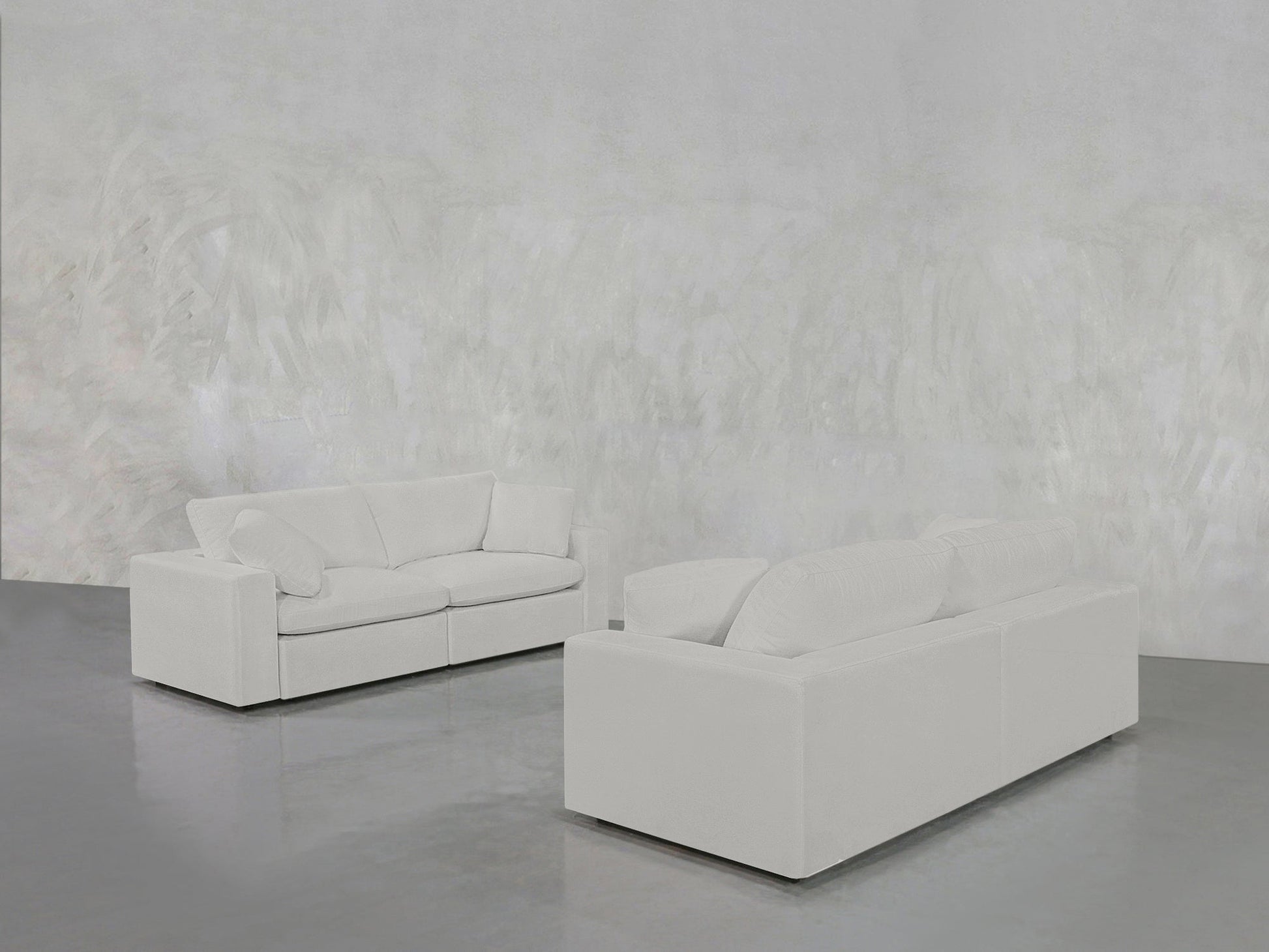 The 2-2 Sofa Set in modern white stands on a gleaming gray floor within a minimalist room featuring textured light gray walls.