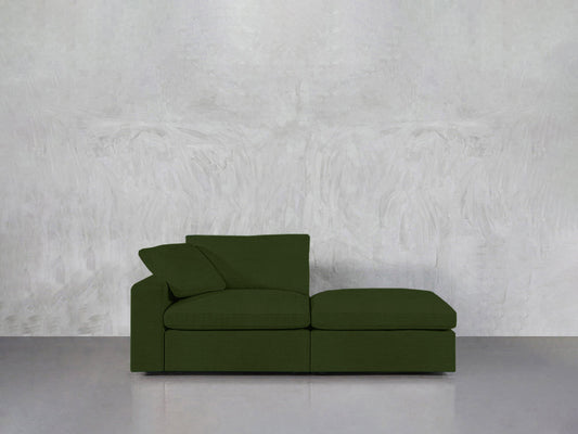 A sleek green 2-Seat Modular Lounger Loveseat with a matching cushion is placed against a textured light gray wall on a smooth gray floor.