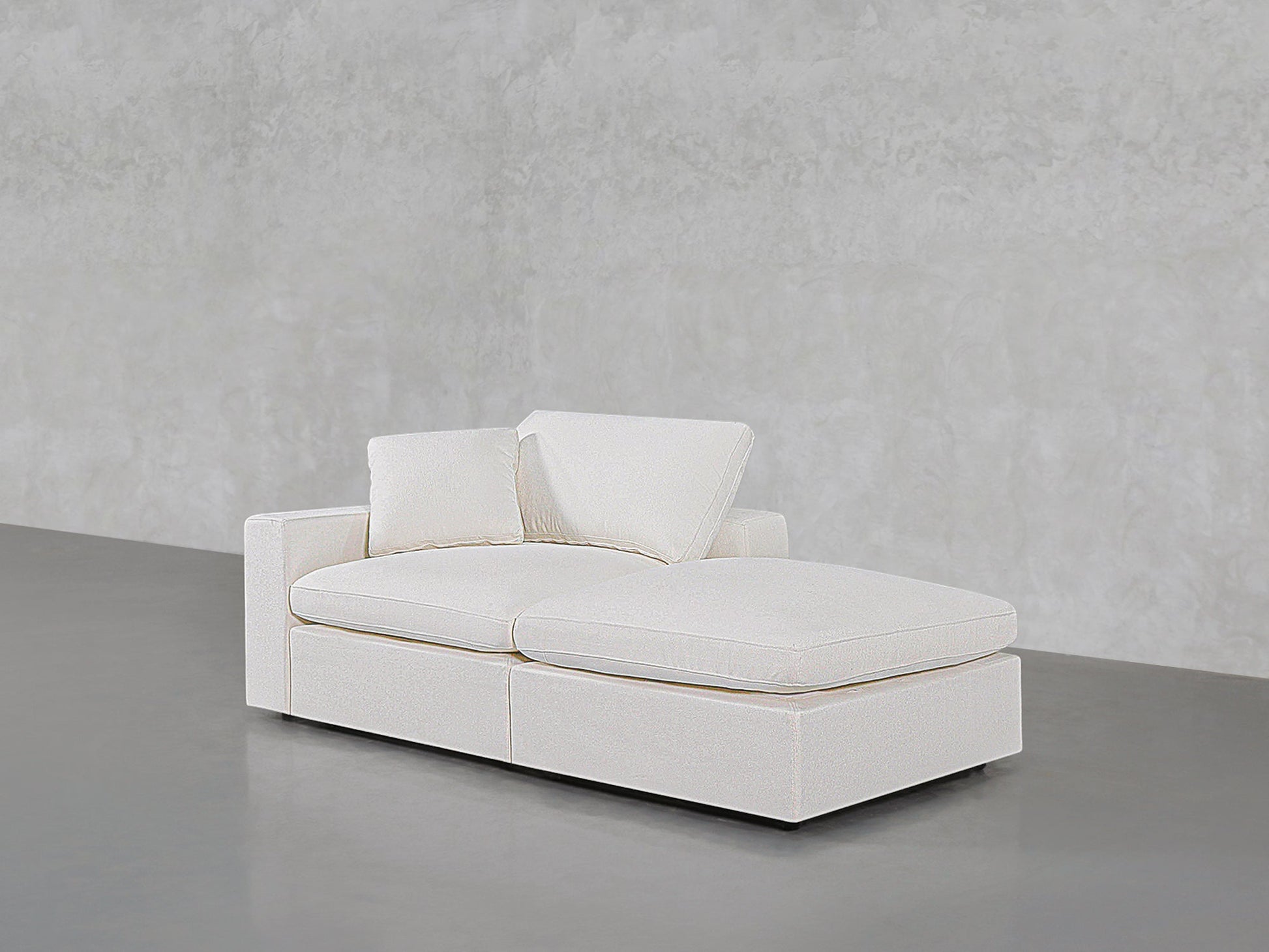 A modern 2-Seat Modular Lounger Loveseat in white upholstery with two cushions, set against a light gray textured wall on a smooth gray floor.