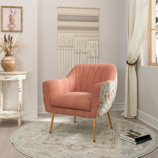 The Accent Chair - Rose Pink with floral-patterned sides sits on a round patterned rug in a cozy room featuring a white table, dried flowers, wall art, sheer-curtained window, and an open book on the floor.