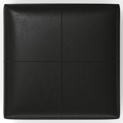 The Gabbie Coffee Table Upholstered Storage Ottoman is black and rectangular, divided into four equal sections by visible seams. Seen from above, its surface has a smooth, slightly glossy finish.