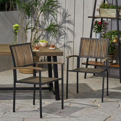 Two Vermilion Outdoor Dining Chairs with vertical slats and wooden arms stand on a stone patio next to an outdoor table topped with drinks and plants. In the background, potted plants and flowers are displayed on a shelf.