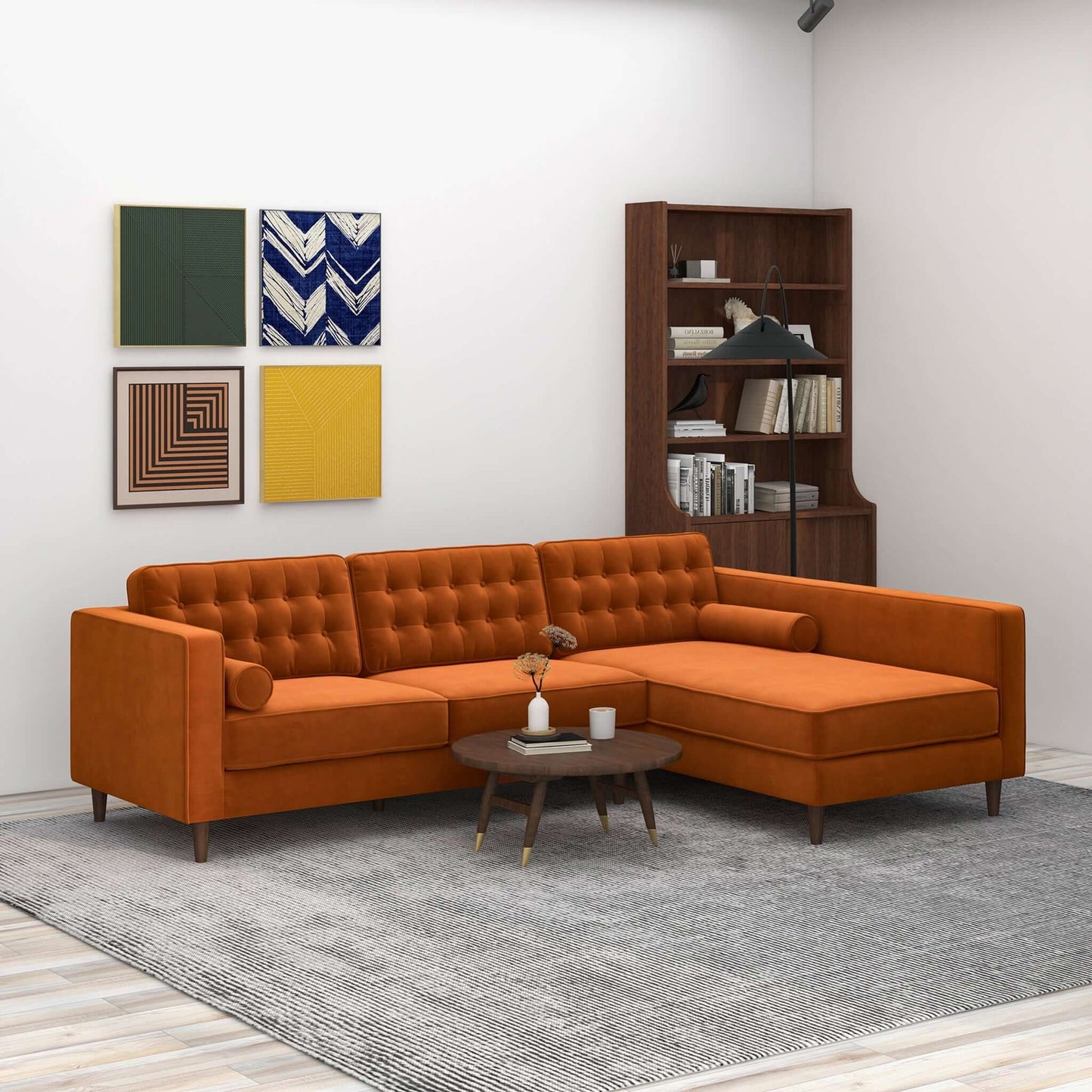 A modern living room featuring the Christian Mid-Century Modern Design Sectional Sofa in orange, a round wooden coffee table, gray rug, wooden bookshelf, and four grid-arranged wall art pieces on a white wall.