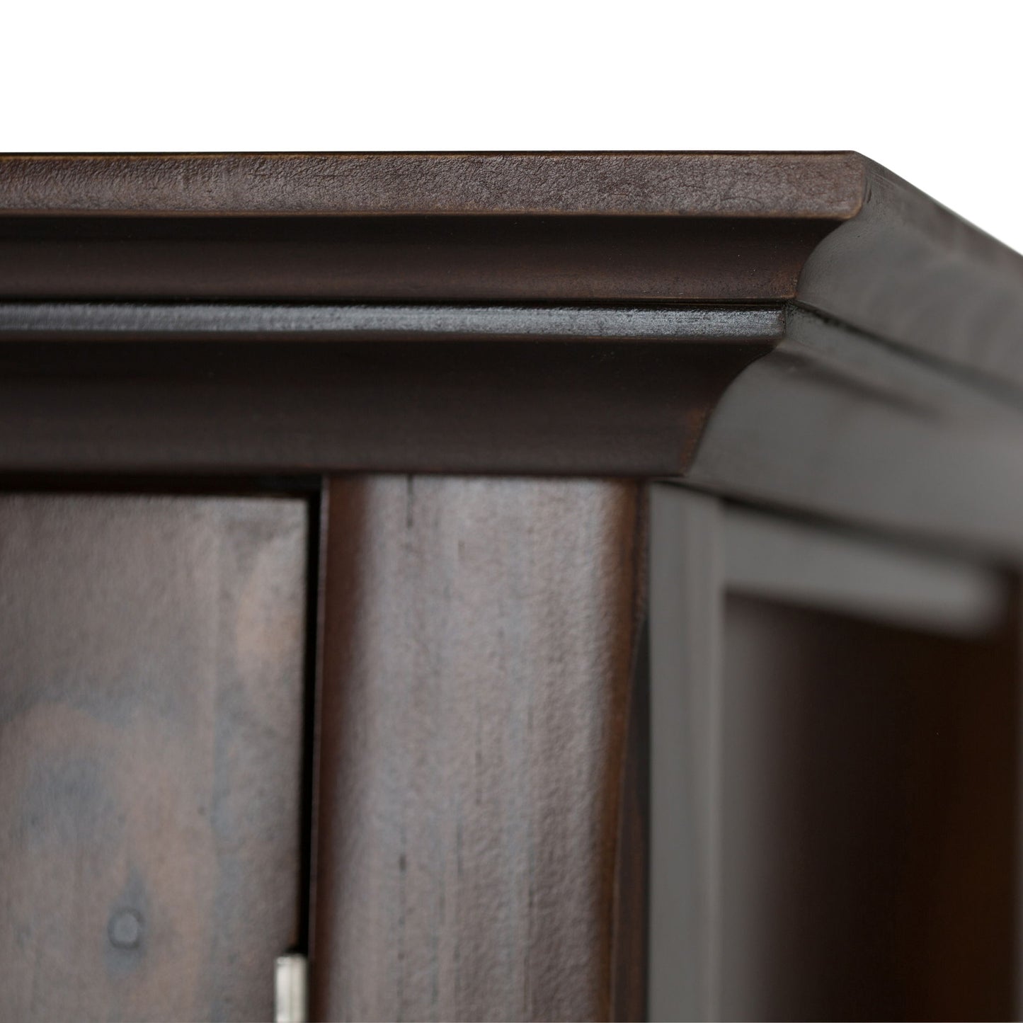 Close-up of the top corner of the Acadian Low Storage Cabinet in Brunette Brown, highlighting its detailed molding and smooth, polished dark wood finish against a white background.