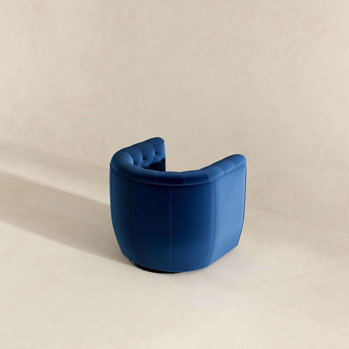 The Delaney Ergonomic Design Swivel Chair, featuring blue semi-circular upholstery with tufted details, sits in a minimalistic neutral-toned room, positioned with its back to the viewer.