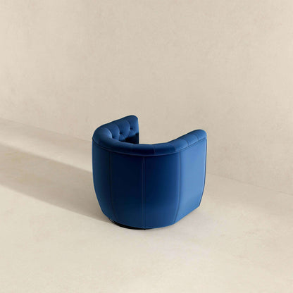 The Delaney Ergonomic Design Swivel Chair, featuring blue semi-circular upholstery with tufted details, sits in a minimalistic neutral-toned room, positioned with its back to the viewer.