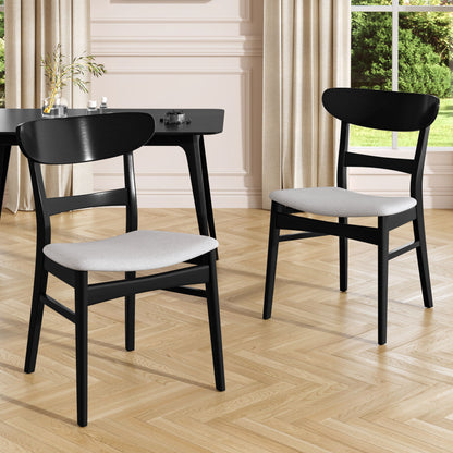 A pair of Mid Century Dining Chairs With Cushioned Seats And Wood Frame (Set of 2) in black are positioned on a light wood herringbone floor, with cream curtains, a window, and a black desk in the bright room background.