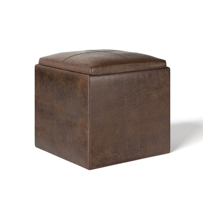 The Rockwood Upholstered Cube Storage Ottoman With Tray features a brown faux leather finish, a cushioned top, and is shown against a white background.