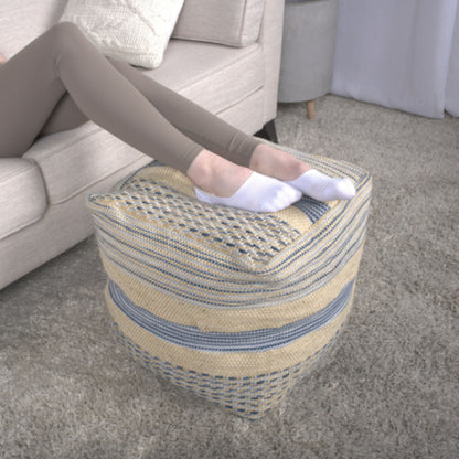A person wearing white socks and beige leggings rests their feet on the Western - Handcrafted Fabric Pouf, Durable - Natural / Blue in a living room with a beige sofa and light gray carpet.