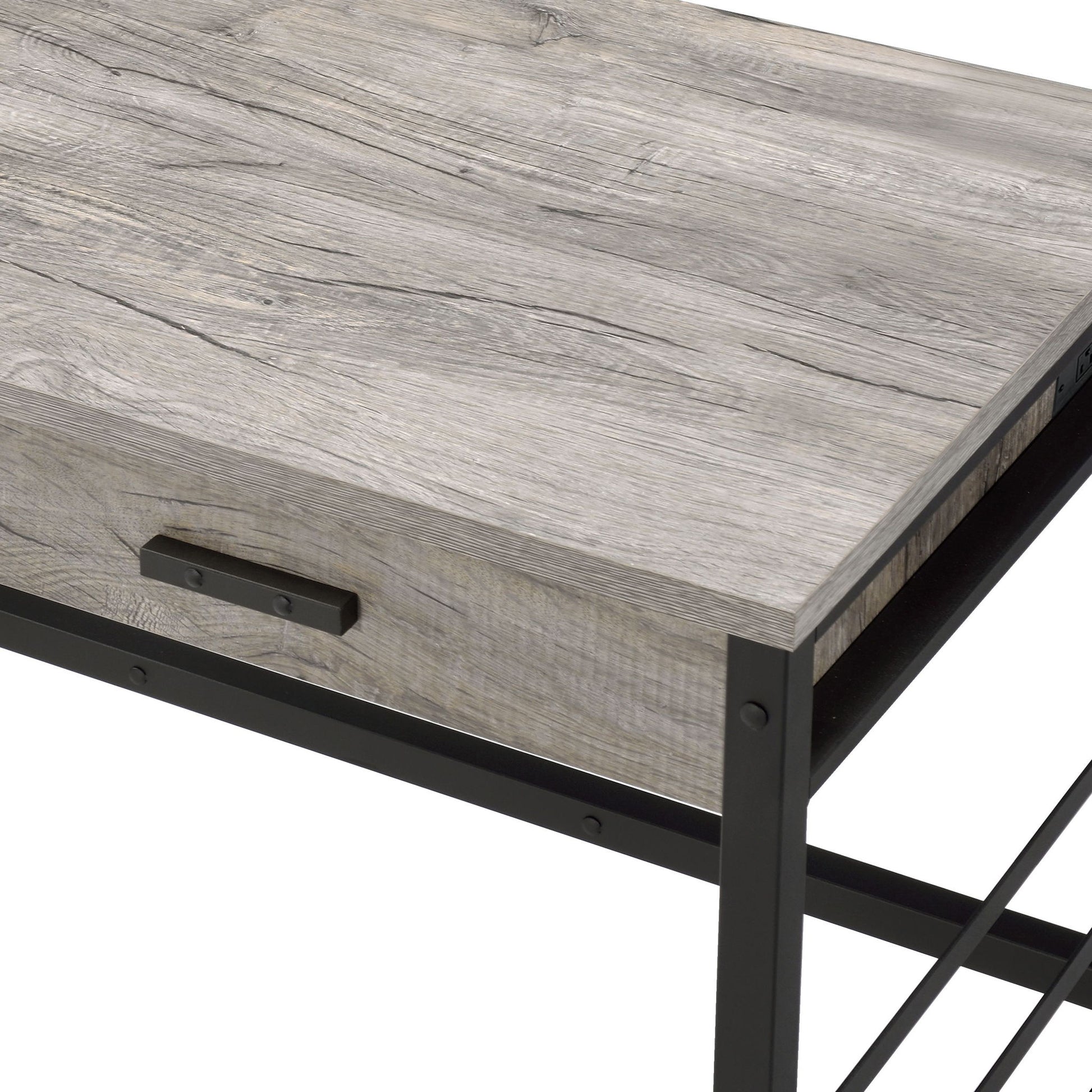 A close-up view of the Disho - Weathered Writing Desk With USB - Oak, showcasing its light gray oak wood surface, black metal frame, and a drawer with a simple metal handle.