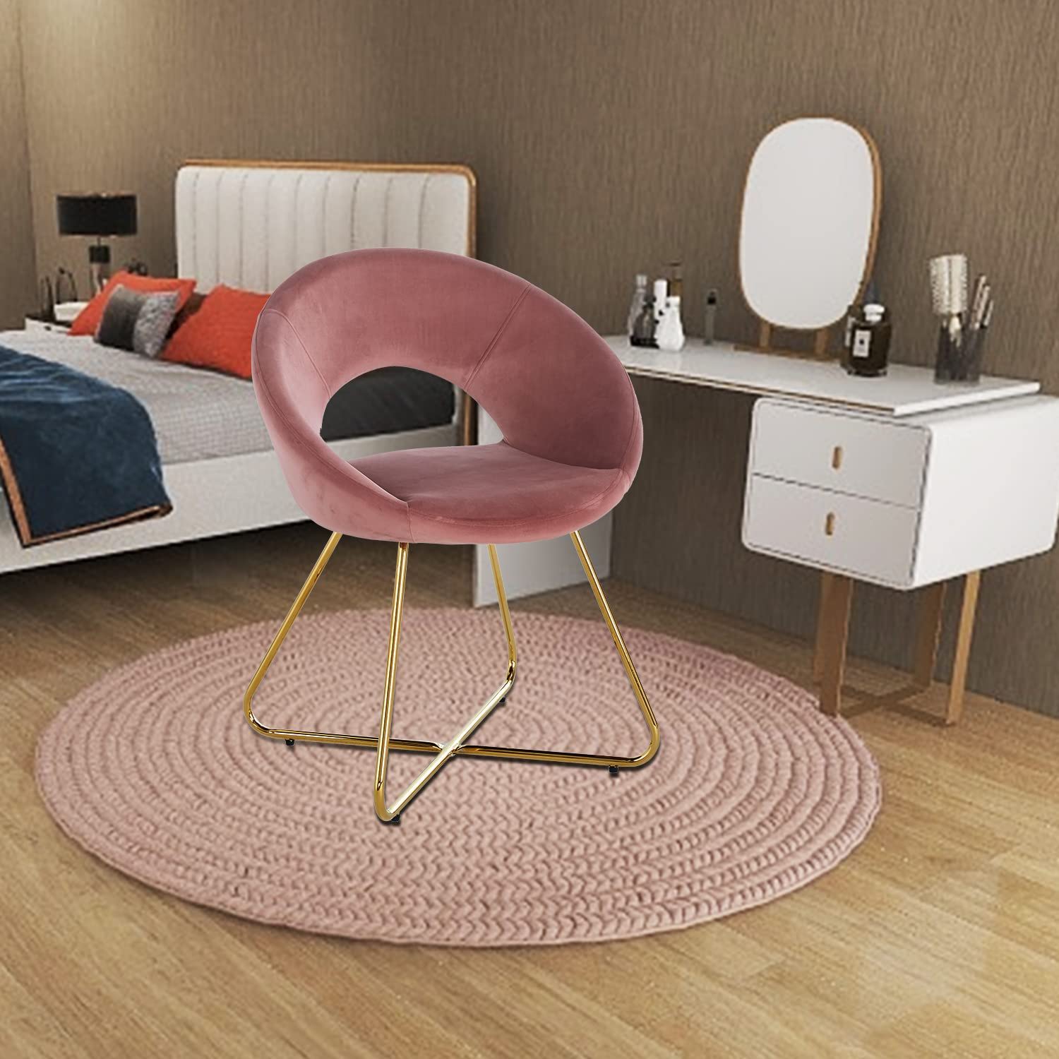 A modern bedroom featuring a white bed, orange and blue pillows, a white vanity with mirror, and the Modern Accent Velvet Lounge Chair with gold legs on a round pink rug over wooden flooring.