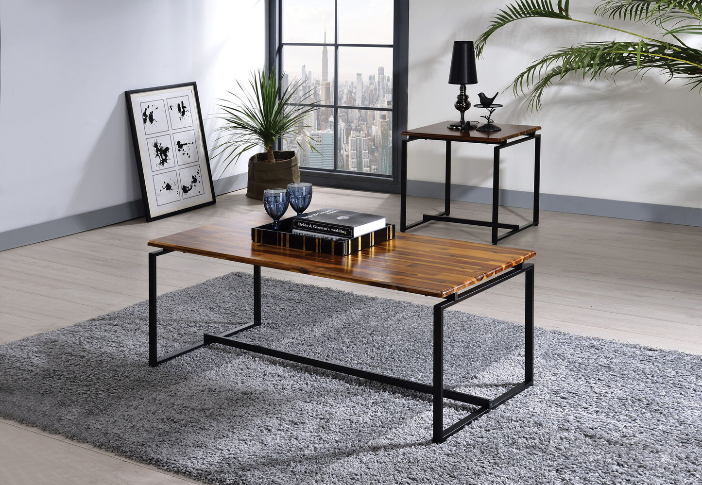 Modern living room featuring the Jurgen - 3 Pieces Pack Coffee & End Set in oak/black on a gray rug, with a plant, decor accents, framed art against the wall, and a city view window in the background.