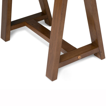 A close-up of the wooden legs and crossbar support of the Sawhorse - Handcrafted Desk, featuring a warm brown finish, set against a white background.