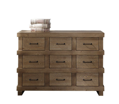 The Adams - Antique Dresser in Brown Oak features nine drawers with black handles, four short legs, and has three books stacked on its top left corner. The dresser is set against a plain white background.