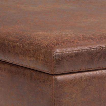 A close-up of the Owen - Multifunctional Square Coffee Table Storage Ottoman highlights its brown leather finish, textured and distressed details, and fine stitching on the corner.