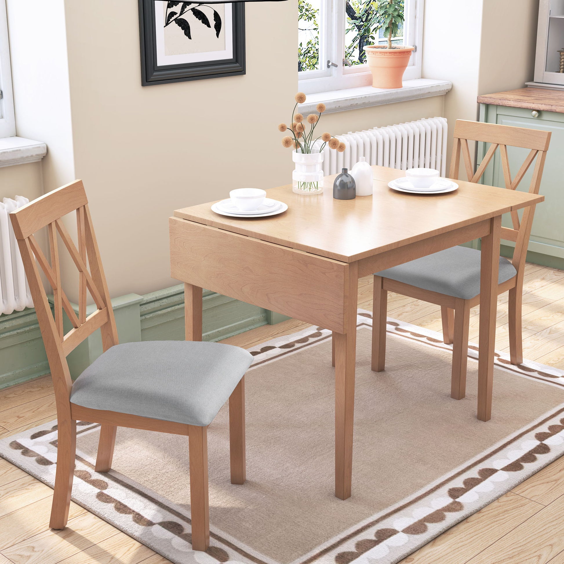 A 3 Piece Kitchen Dining Set with a drop leaf table and 2 upholstered chairs is placed on a beige rug in a bright kitchen with light green cabinets, set with white plates and cups near a window—perfect for small spaces.