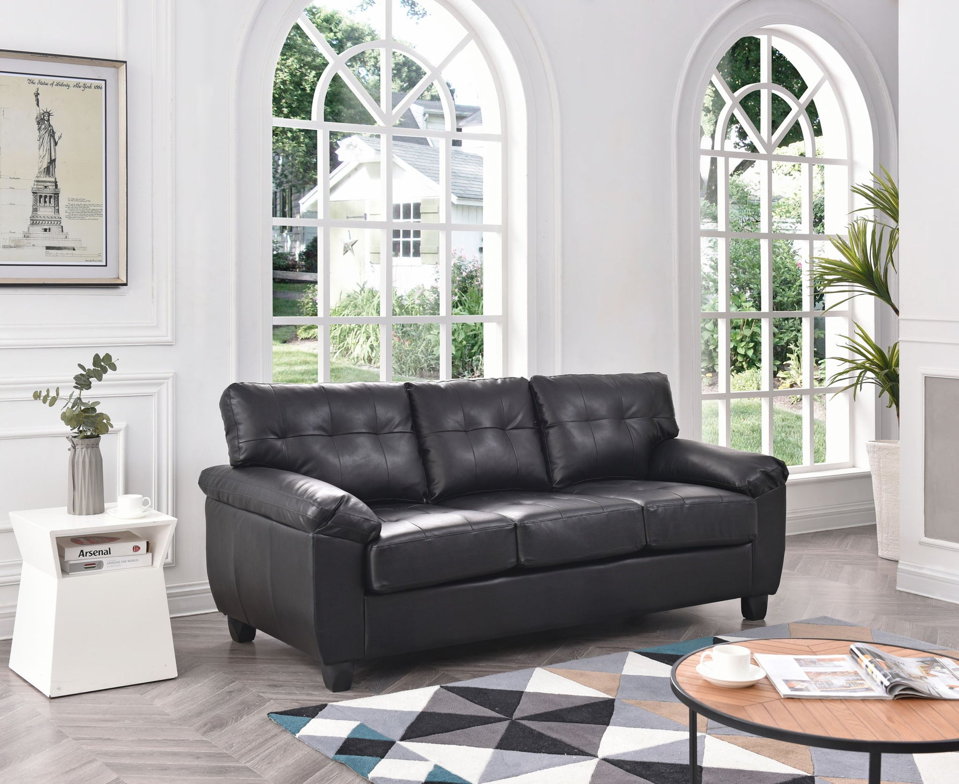The Comfortable Sofa sits in a bright living room with arched windows, a geometric rug, a white side table with a plant, and a round coffee table. Sunlight streams in, emphasizing the modern minimal décor.