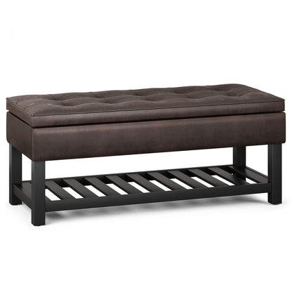 The Cosmopolitan Storage Ottoman Bench features a rectangular, tufted brown upholstered seat, black wooden legs, and an open-bottom slatted shelf for storage.