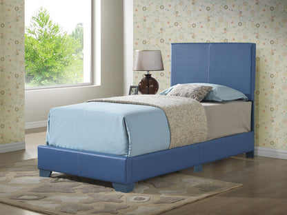 An Elegant Platform Bed For Relaxed Spaces with a blue upholstered frame and headboard sits in a sunlit room. Light blue and gray bedding complements it, with a lamp and clock on the nightstand beside the bed. Greenery is visible through the window.