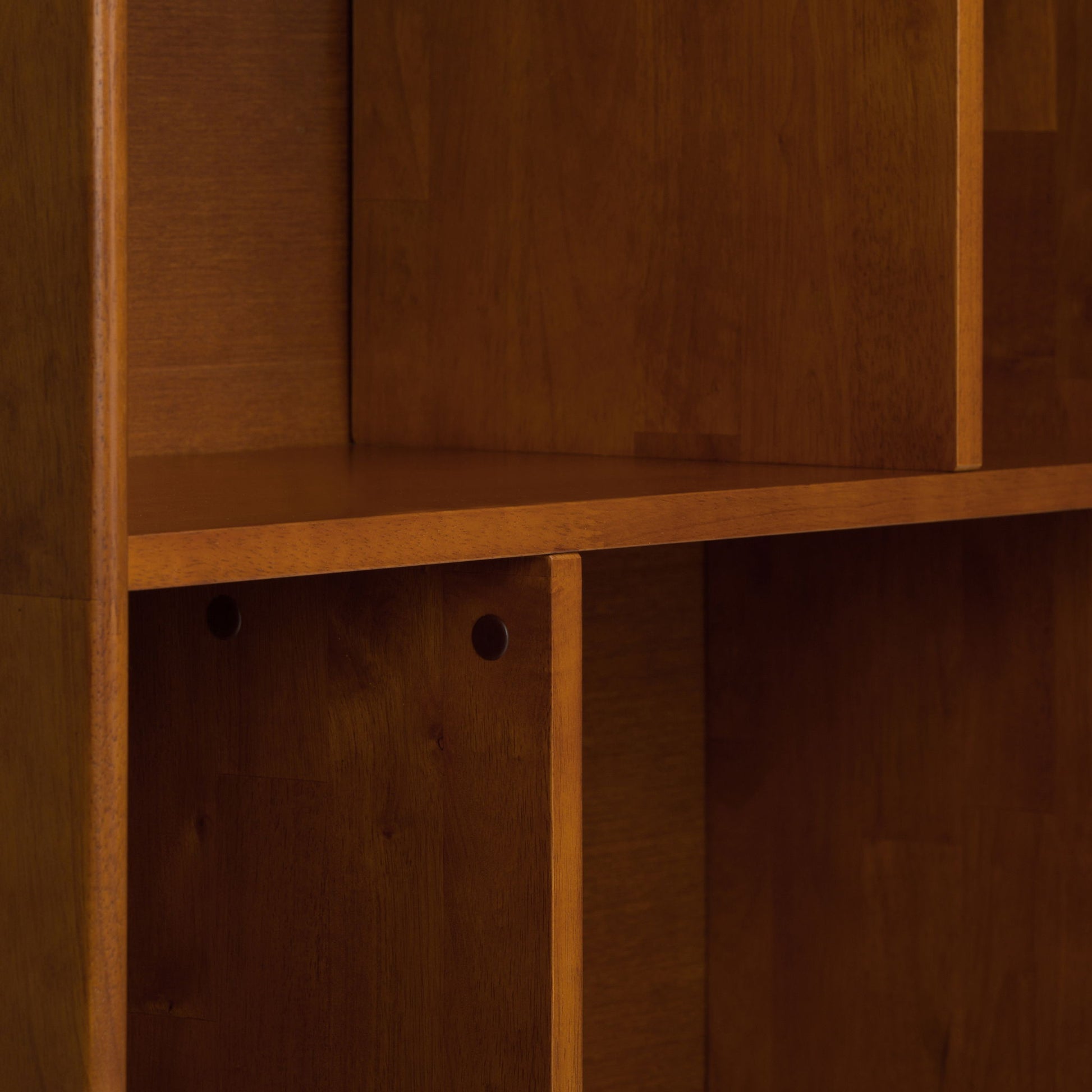 Close-up of the Draper - Mid Century Wide Bookcase And Storage Unit, featuring empty compartments and vertical dividers in a natural brown finish, showcasing its clean shelves, visible wood grain, and smooth texture.