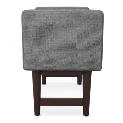 The Scott Upholstered Ottoman Bench in grey features dark wooden legs and is displayed from the back against a white background.