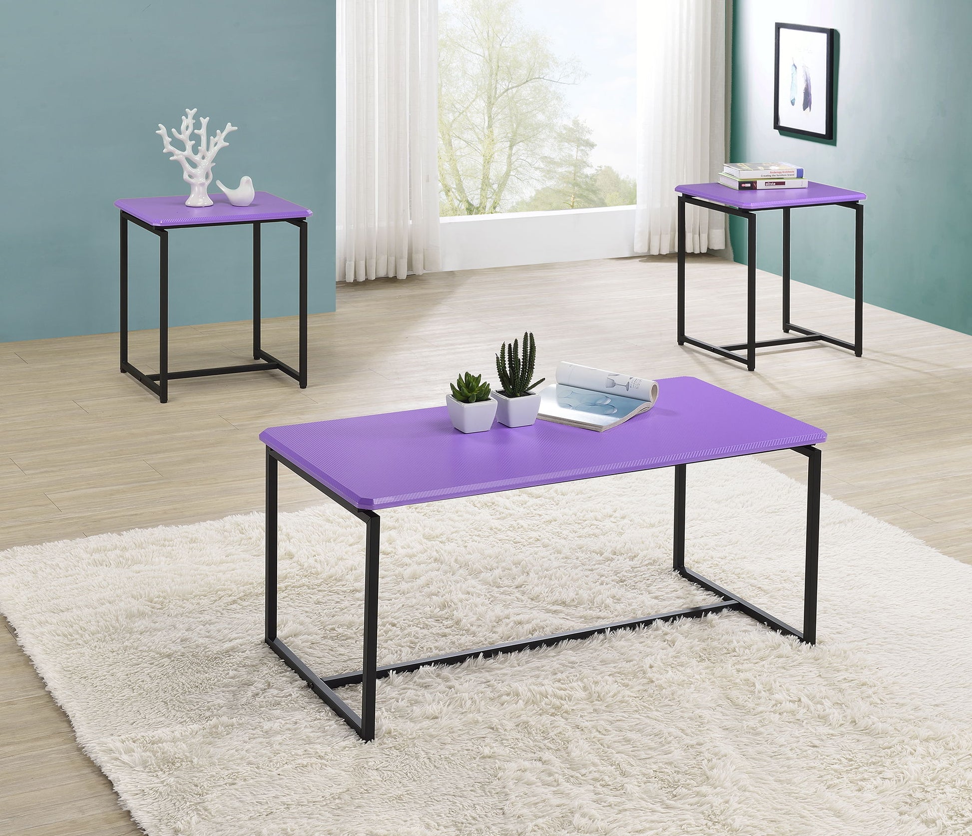 The GT 3 Piece Carbon Fiber Wrap Coffee Table and End Table set, with sleek purple tops and black metal legs, is arranged on a light wood floor with a white rug in a bright room featuring large windows, sheer curtains, and framed art on blue walls.