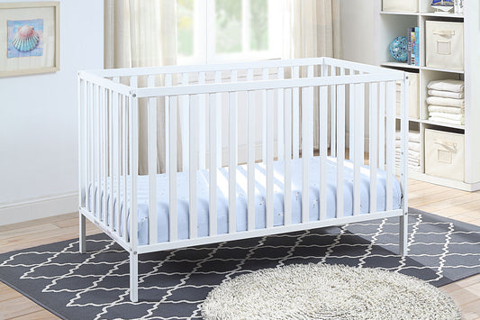 The Palmer - 3-in-1 Convertible Island Crib with a light blue mattress stands on a patterned gray rug in a bright room featuring shelves, baskets, and a window with cream curtains in the background.