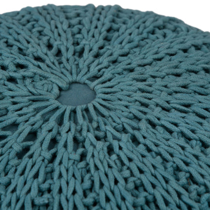 Close-up of the Shelby - Handcrafted Hand Knit Round Pouf, featuring a round, teal design with a central opening and thick, textured yarn in an intricate open-weave pattern.