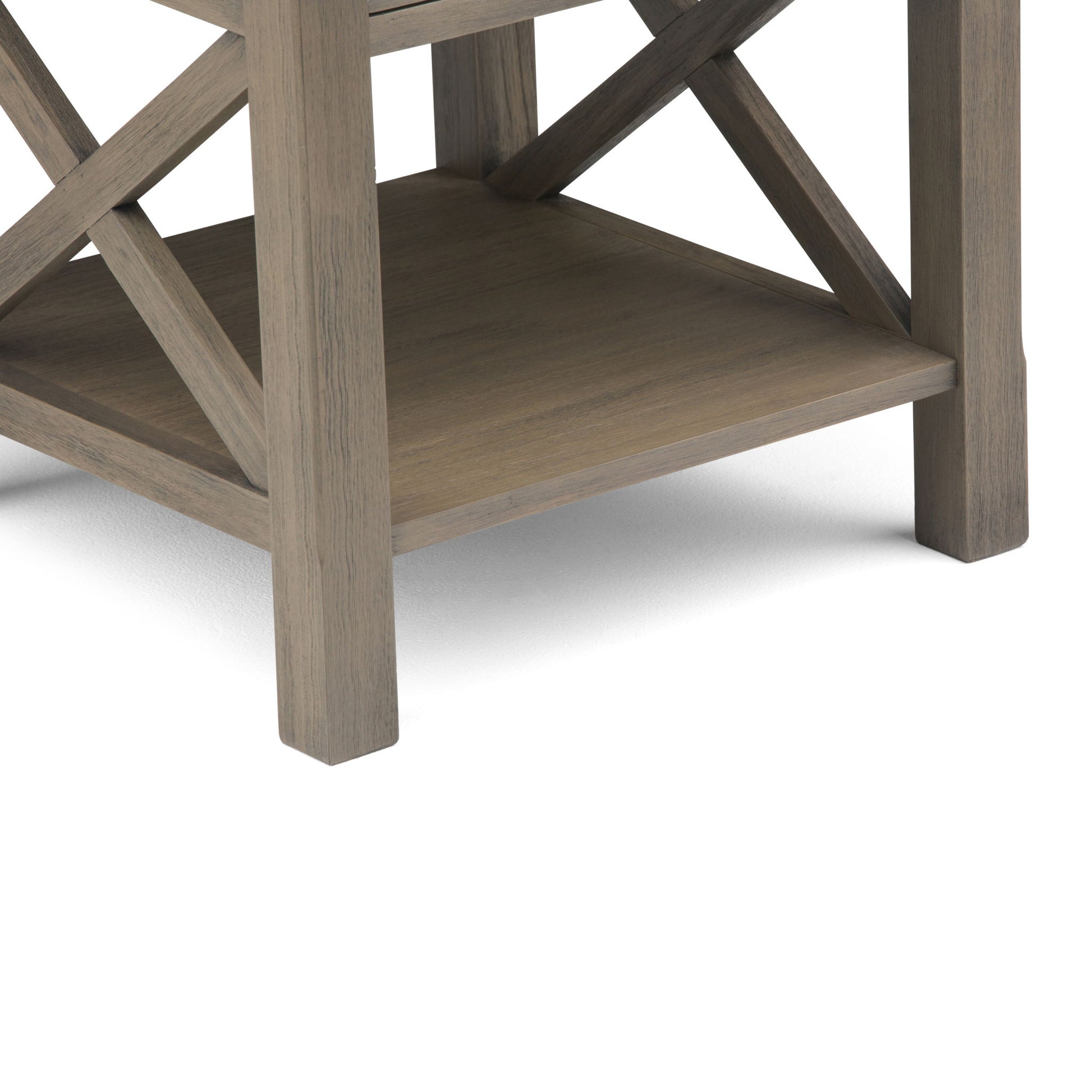 Close-up of the Kitchener - Handcrafted Table’s lower section, showcasing a square lower shelf and X-shaped side supports in a grayish-brown wood finish, all set against a white background.