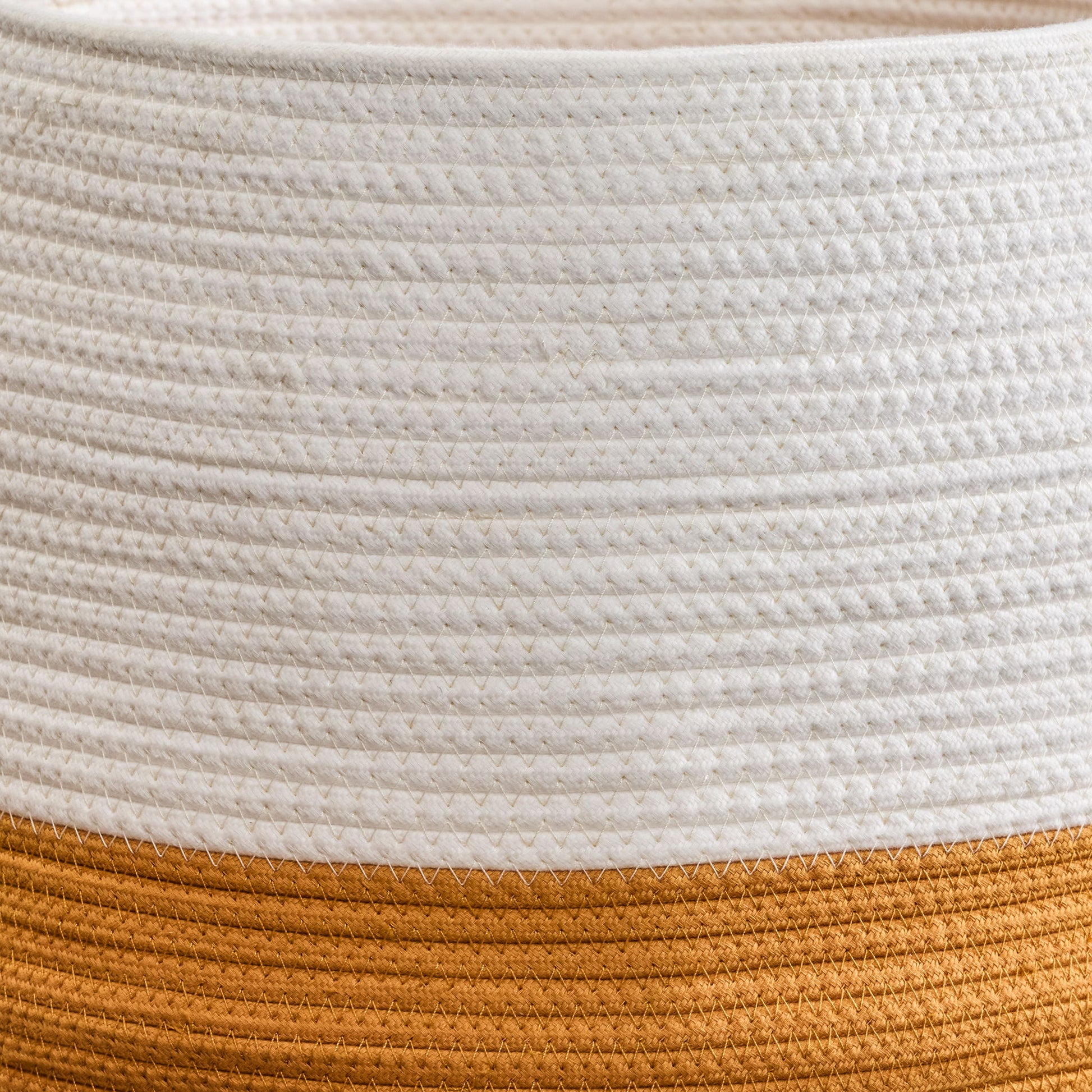 Close-up of the Francis - Cotton Round Laundry and Storage Basket, showcasing its textured woven surface with a thick white band on top and a wide golden-brown band at the bottom.