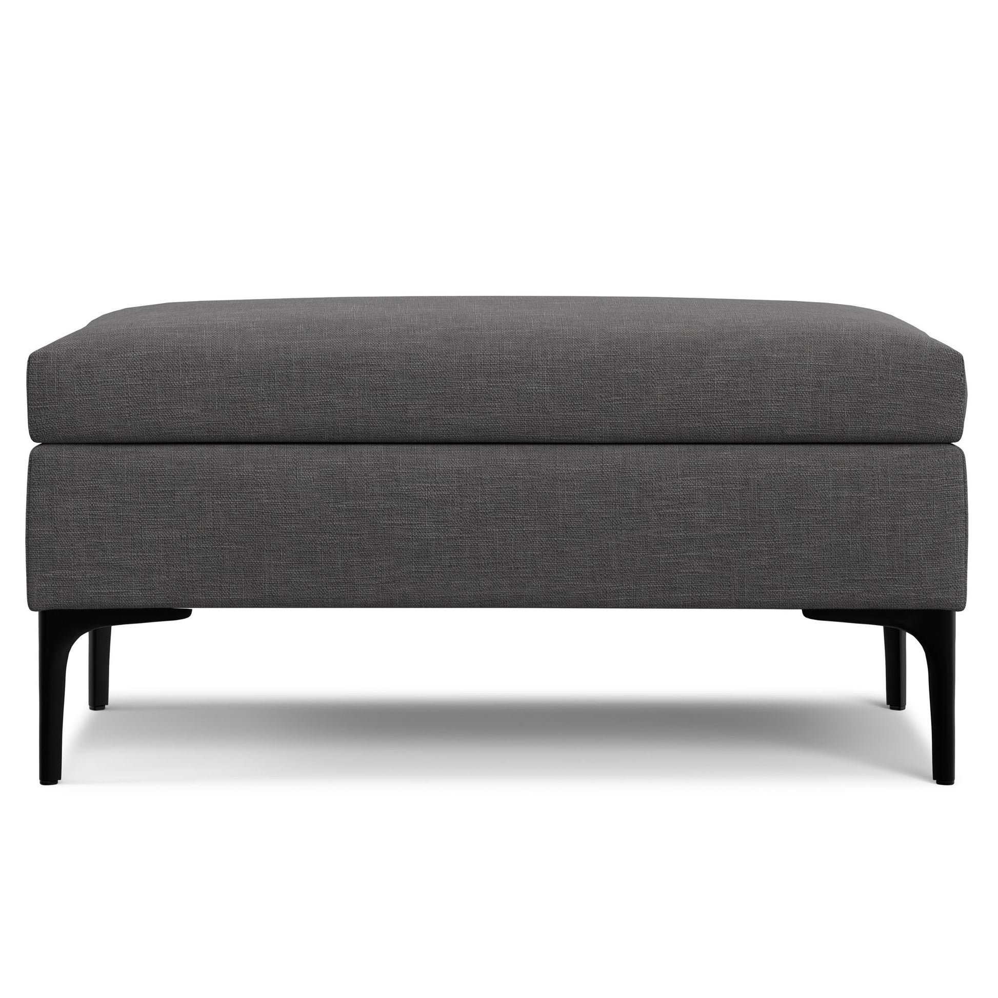 The Rebecca is a rectangular, dark gray upholstered storage ottoman with a cushioned lift-up lid and black legs, displayed against a white background.