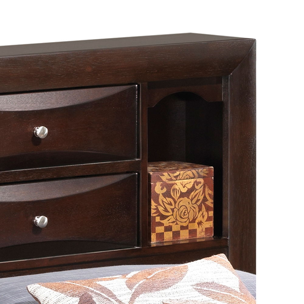 Close-up of the Marilla Storage Bed with Bookcase Headboard, showing two drawers with round silver knobs, an open shelf with a floral decorative box, and part of a pillow with a leaf design in the foreground.