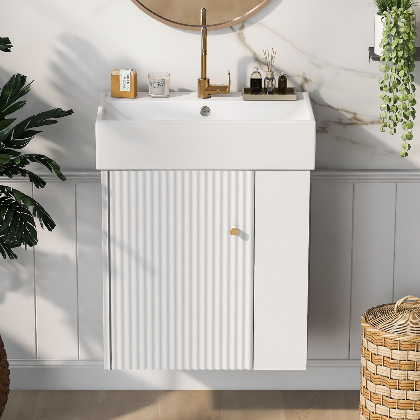The Modern Floating Bathroom Vanity With Ceramic Basin, ideal for small bathrooms, features a white sink and ribbed cabinet doors, set against marble and white-paneled walls with gold accents, decor items, a potted plant, and a wicker basket nearby.