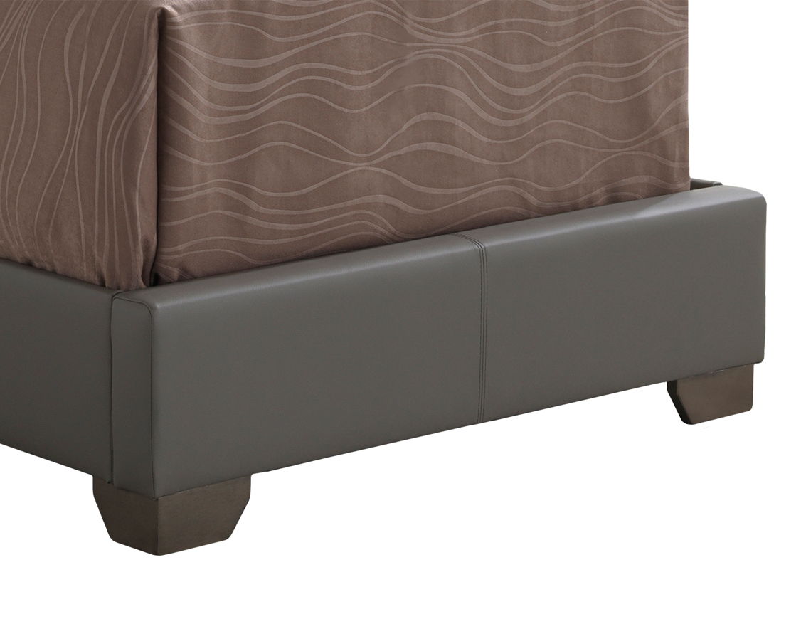 The image shows the lower corner of the Elegant Platform Bed For Relaxed Spaces with a gray upholstered frame, dark wooden legs, and a brown bedspread featuring a wavy line pattern.