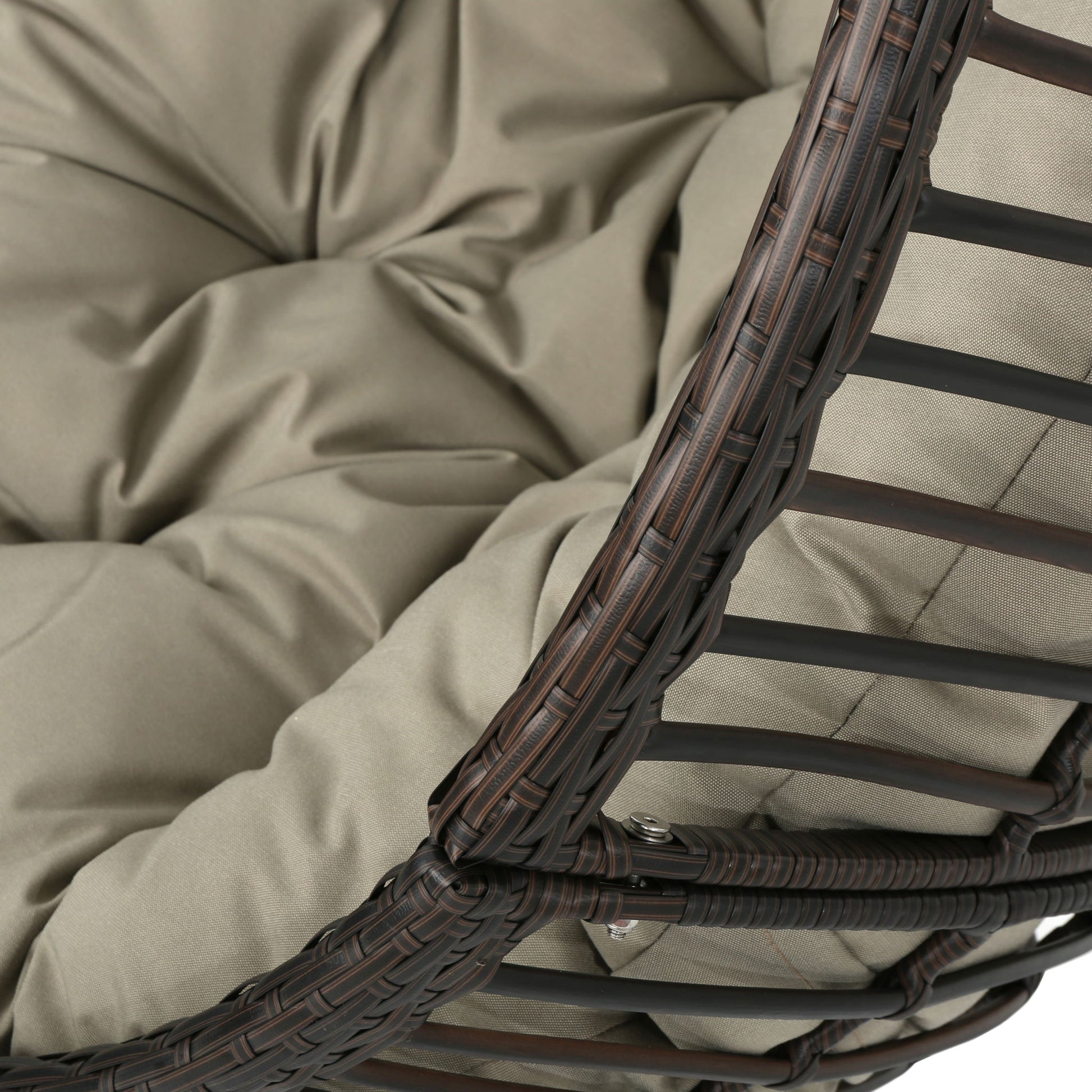 Close-up of the Hanging Basket Chair with a metal frame, seat cushion in light beige tufted fabric, and a rounded dark brown wicker exterior.