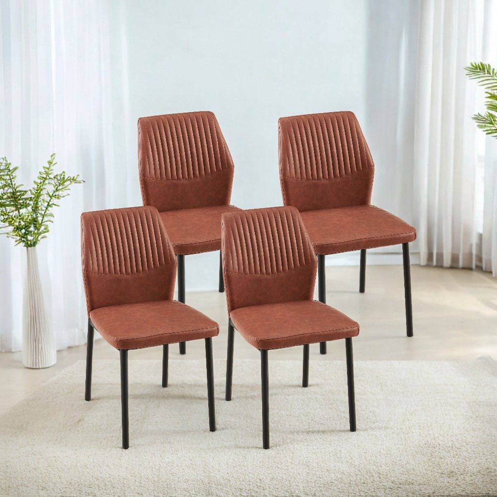 Four Modern Kitchen Armless Side Chairs with brown upholstery, ribbed backs, and black metal legs are set on a light carpet in a bright room with large windows, sheer curtains, and green plants in white vases.