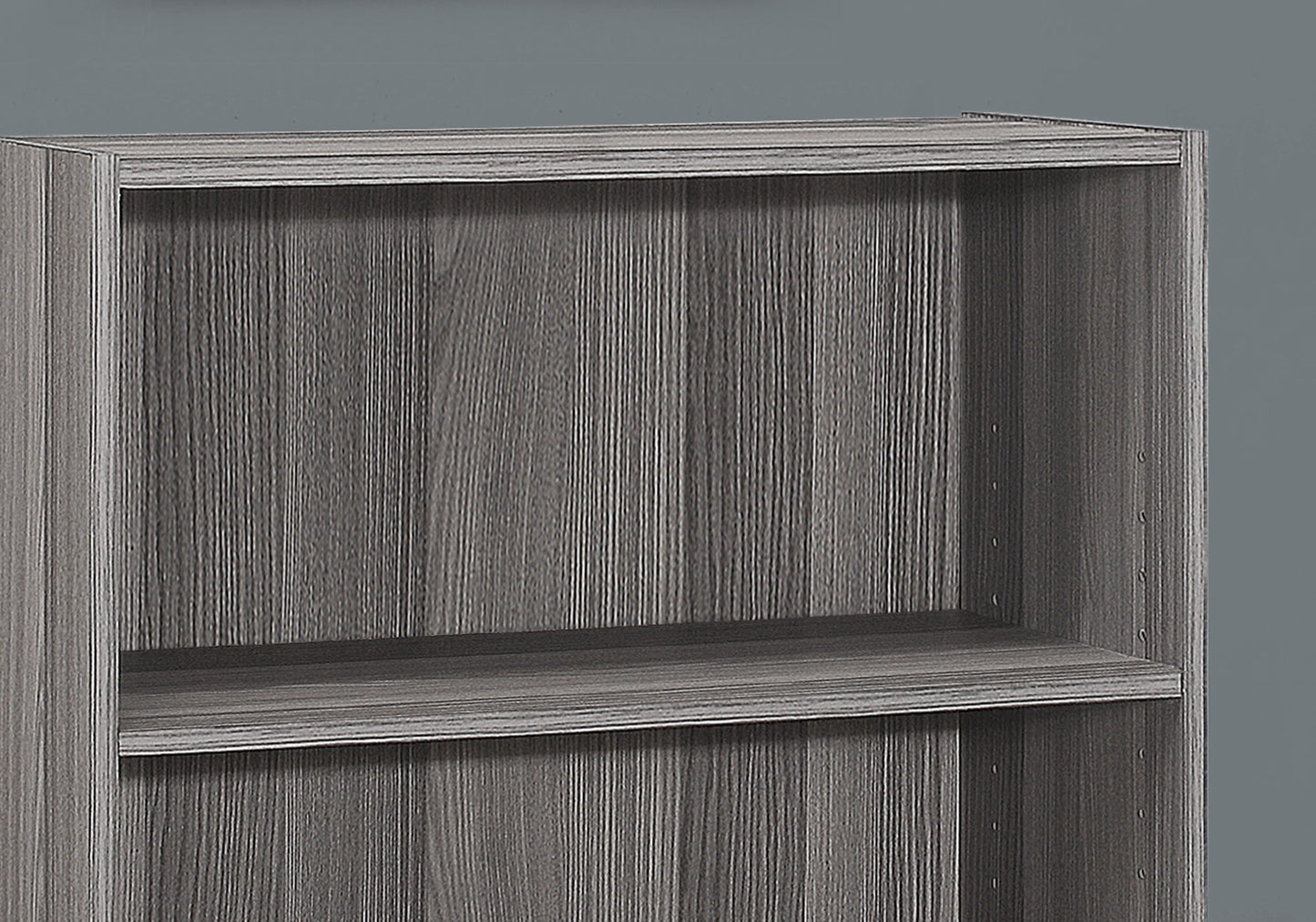 A close-up of a gray, 4-tier bookshelf with a modern, wood grain texture and transitional design, ideal for office use, set against a plain gray background.