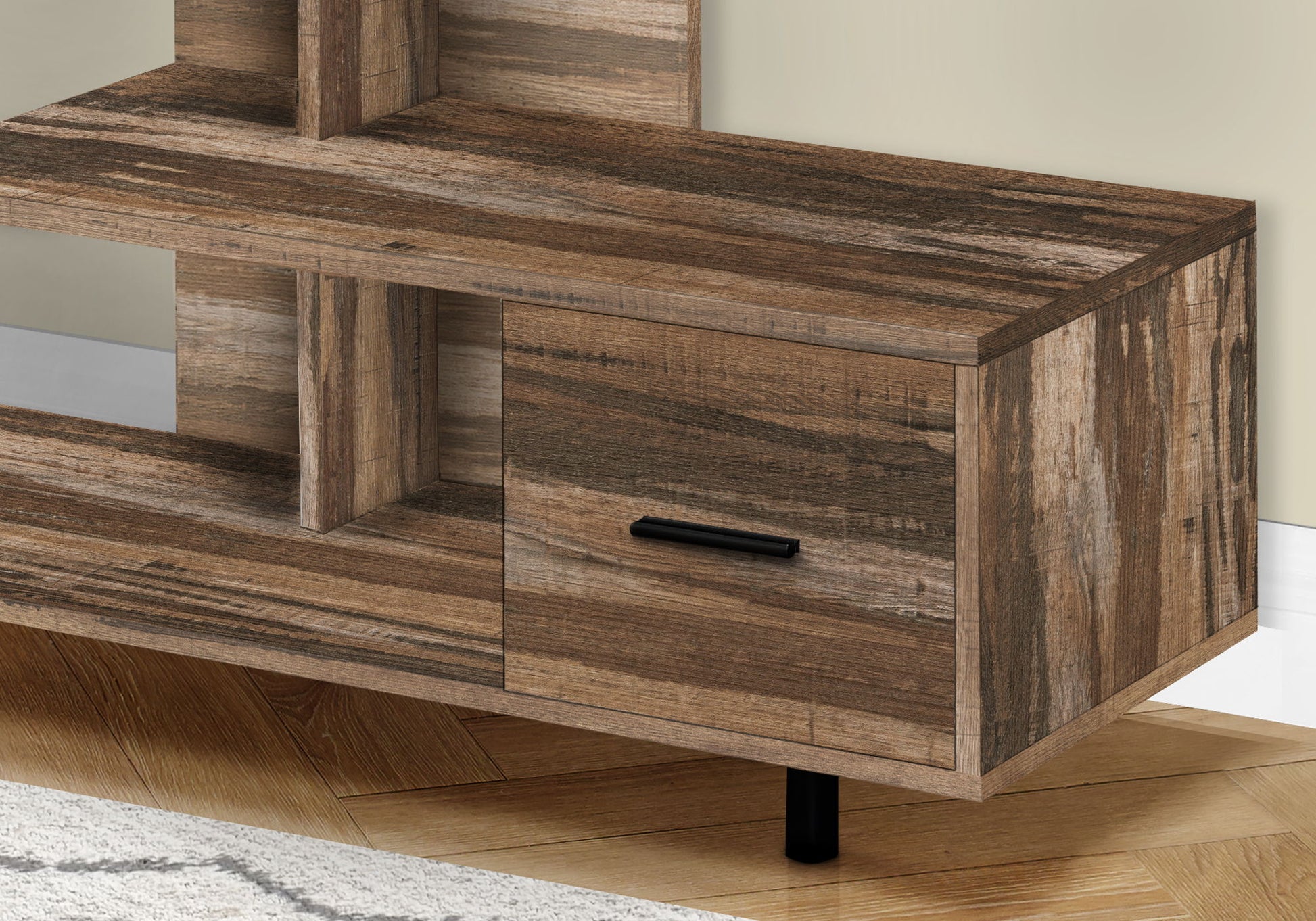 A close-up of the contemporary TV Stand, Console, and Media Entertainment Center with a rustic finish, open shelf, storage drawer with a black handle. It sits on a wooden floor beside a light-colored wall and part of a rug.