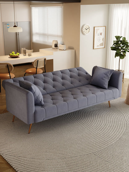 A modern living room features a Convertible Double Folding Living Room Sofa Bed with two pillows on a round textured rug, near a dining area with two chairs, kitchen, wall clock, framed art, and a potted plant by the window.