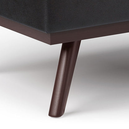 Close-up of a dark wooden leg supporting the Owen Lift Top Large Coffee Table Storage Ottoman, featuring dark upholstery and a clean, modern mid-century design on a white background.